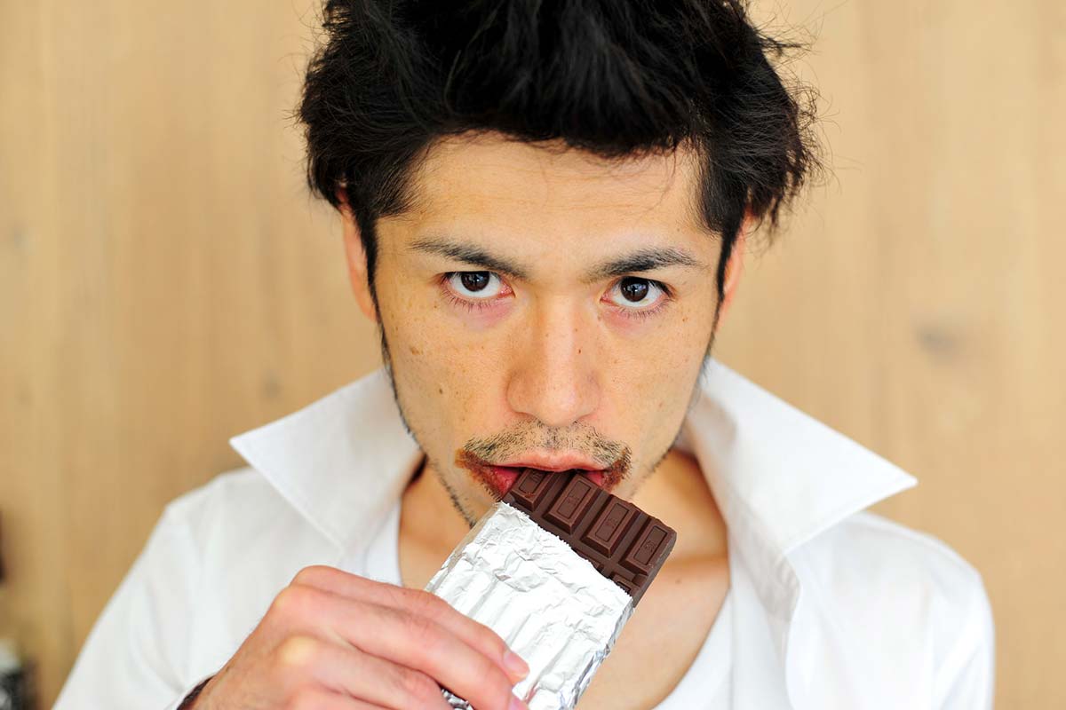 板チョコレートを噛んでいる男性