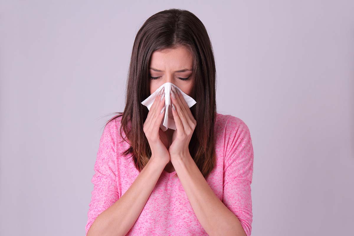 鼻をかむ花粉症に苦しむ女性