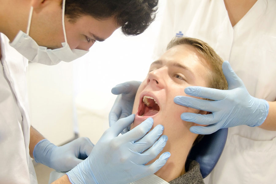 口を歯科医に見せる患者