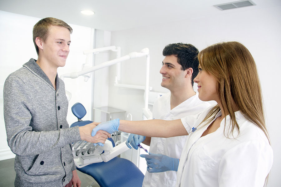 握手をする歯科医と歯科衛生士と患者