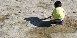 砂場で寂しそうな背中を見せる子供