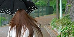 傘をさして歩く髪の長い女性