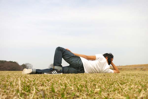 芝生の上で寝そべる男性